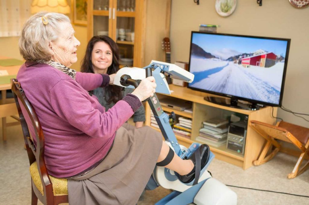 Older adult women riding an exercise bike while testing out the Motitech technology, technology that helps older adults and individuals with dementia become more physically active.