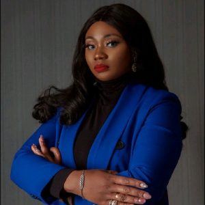 Vivian Ufodike, who stands to the right with her arms crossed in a blue blazer. 