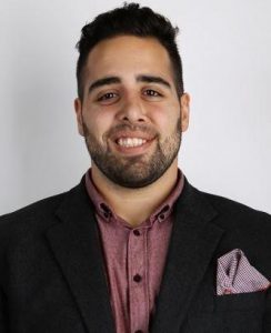 A profile image of Xtreme Accelerator Program applicant Stuart Anoya, who's smiling wearing a blazer and a purple shirt.