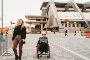 A person in a wheelchair is joined by a support person outside of TD Place in Ottawa. 