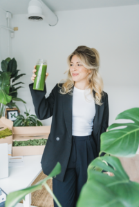 Founder of The Urban Botanist Emma Terrell, is dressed in business attire surrounded by greenery. 