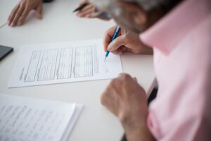 An overhead view of an individual who appears to be signing documents. 